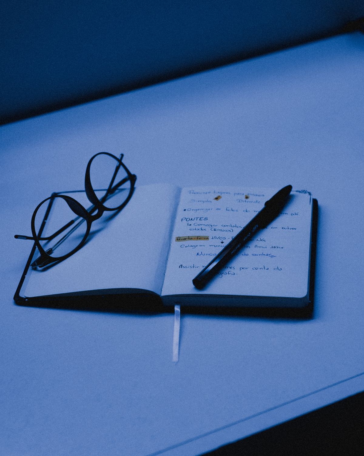 An open notebook with a pen and eyeglasses on a desk, capturing the essence of studying or planning.